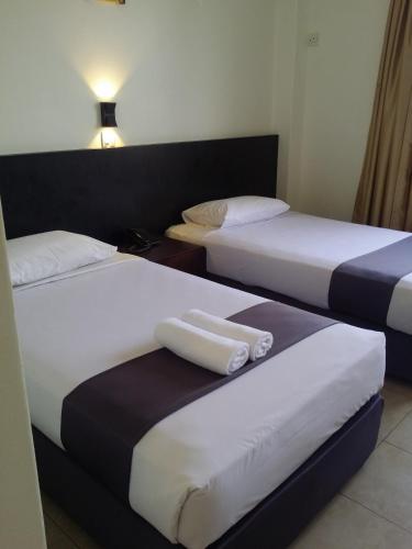 two beds in a hotel room with towels on them at Seremban Inn in Seremban
