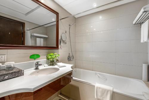 杭州的住宿－杭州海外海国际酒店，浴室配有盥洗盆、镜子和浴缸