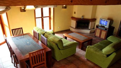 a living room with a couch and a table and a television at La Badila in Garganta de los Montes