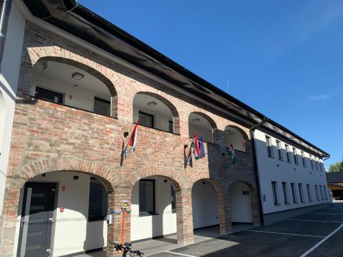 a brick building with arches and flags on it at M70 Apartmanház in Miskolc