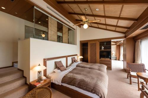 a master bedroom with a bed and a staircase at Nishiizu Crystal View Hotel in Nishiizu