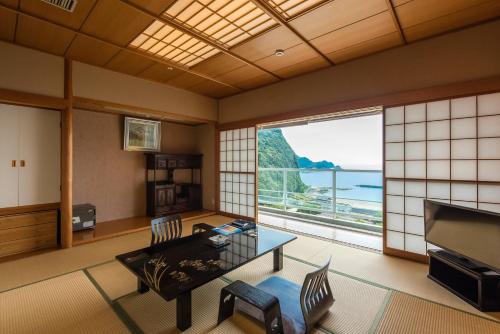 a living room with a table and a large window at Nishiizu Crystal View Hotel in Nishiizu