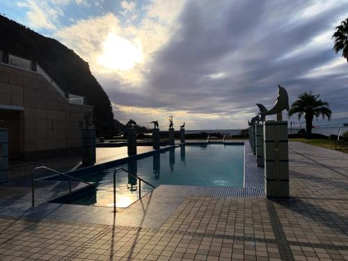 a swimming pool with a statue next to a building at Nishiizu Crystal View Hotel in Nishiizu