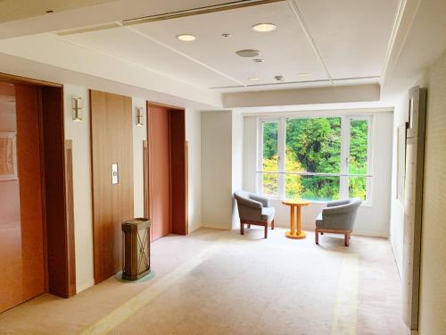 a hallway with chairs and a table and a window at Nishiizu Crystal View Hotel in Nishiizu