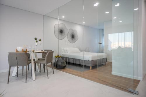 a white bedroom with a bed and a table and chairs at RM Loft in Setúbal