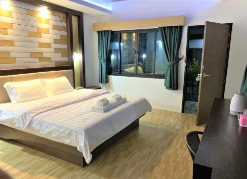 a bedroom with a bed and a desk and window at Thalang resort in Thalang