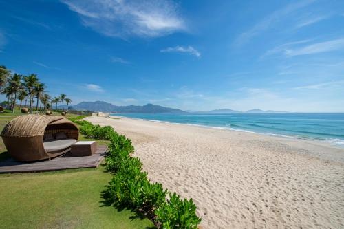 a view of a beach with a boat on it at Fusion Resort Cam Ranh - All Spa Inclusive in Cam Ranh