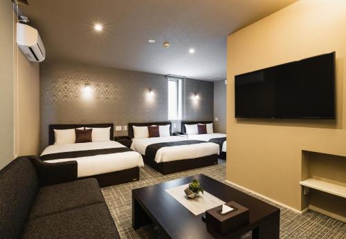a hotel room with two beds and a flat screen tv at GRAND BASE Yakuin Odori in Fukuoka