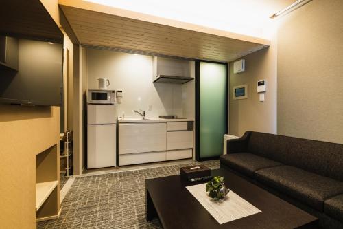a living room with a couch and a kitchen at GRAND BASE Yakuin Odori in Fukuoka