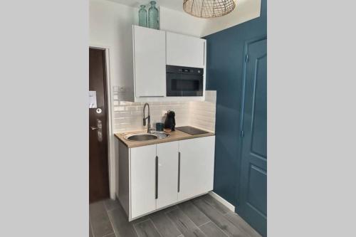a kitchen with white cabinets and a sink at Appart' Studette Cosy - STADE U ARENA in Maisons-Laffitte
