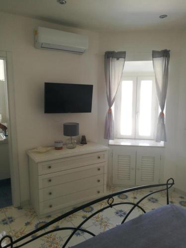 ein Schlafzimmer mit einem TV und einer Kommode mit einem Bett in der Unterkunft Agenzia Isotur MALVA in Ponza
