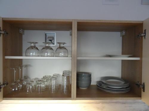 a cabinet with glass jars and plates in it at Tip Top Apartments Kasprowicza in Kołobrzeg