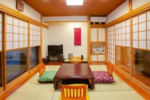 a dining room with a wooden table and chairs at 熱海の海が一望できる温泉付貸別荘 満月あじろ mitsukiajiro in Atami