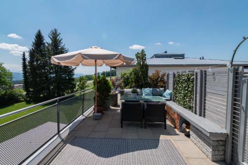 a balcony with an umbrella and a table at Heimelig im Allgäu in Lindenberg im Allgäu
