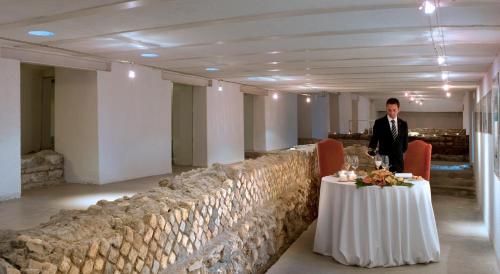 a man standing next to a table in a room at La Posta Vecchia Hotel in Ladispoli