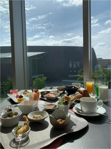 a table with food on a table with a window at Piazza Hotel Nara in Nara