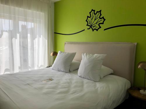 a bedroom with a white bed with a green wall at Sure Hotel by Best Western Argentan in Argentan