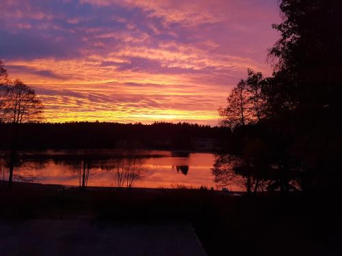 a sunset over a lake with trees in the background at Hotel Chytrov in Volfířov