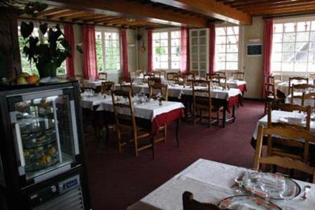 a dining room with tables and chairs and windows at Logis Hotel Du Commerce in Pont-d'Ouilly