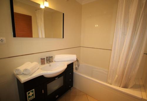 a bathroom with a sink and a bath tub at T1 Praia da Rocha/1ª linha in Portimão