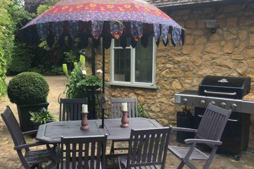 a table with an umbrella in front of a house at THE HIDEAWAY - KENT in Sole Street