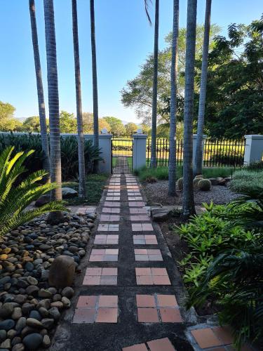 a garden with palm trees and a walkway at Elegant Lodge & Conference Center in Pongola