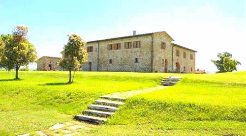 a building in a field with stairs leading to it at Locanda Vesuna Hotel Countryhouse in Pienza