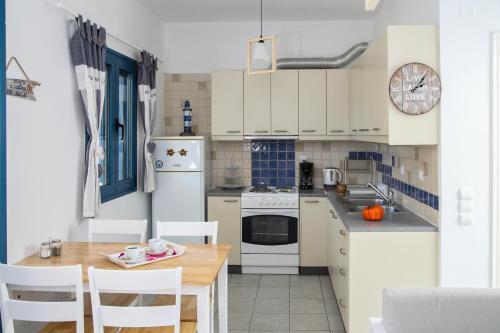 a kitchen with white appliances and a table and chairs at MMM Apartment in Makry Gialos