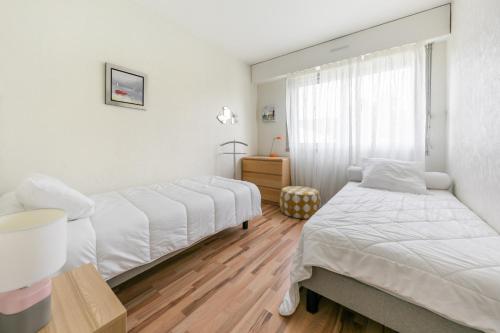 two beds in a room with white walls and wooden floors at Les Terrasses du Palais in Vannes