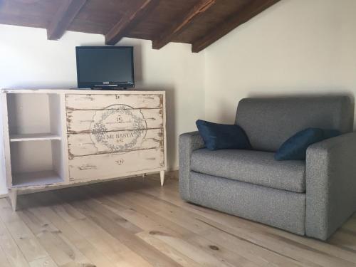 uma sala de estar com uma cadeira, uma televisão e uma cómoda em Terra della Baronia em Santo Stefano di Sessanio