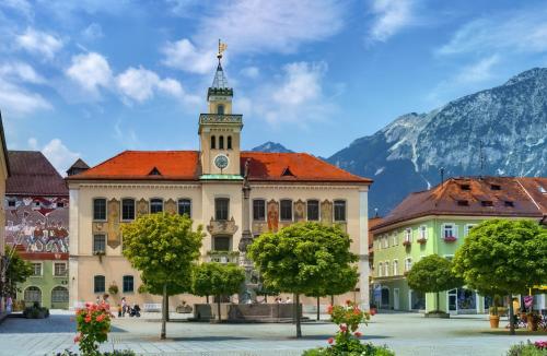 a building with a clock tower with mountains in the background at Pension Almhof Baumgarten in Bad Reichenhall