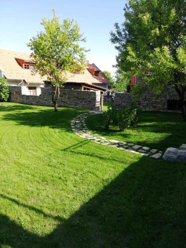 a yard with a stone wall and trees and grass at Arácsi Vendégház in Balatonfüred
