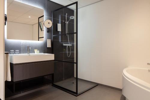 a bathroom with a sink and a shower at Golden Tulip Leiden Centre in Leiden
