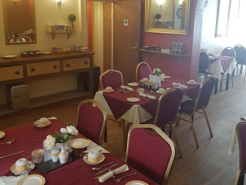 a dining room with two tables and chairs and a table at The Berkeley Guesthouse in Eastbourne