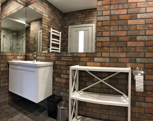 a bathroom with a white sink and a brick wall at Авиатик in Zhytomyr