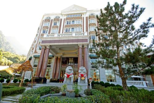 a building with two statues in front of it at Le Midi Hotel Chitou in Lugu