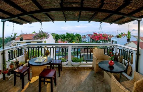 Un patio con mesas y sillas en un balcón. en Green Sand Homestay, en Hoi An
