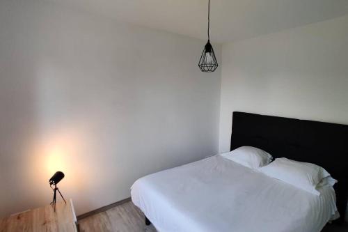 une chambre avec un lit blanc et une lampe dans l'établissement Résidence SAGRADA - Le scandinave, à Toulouse