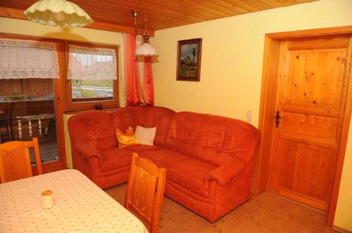 a living room with a red couch and a table at Woferlhof, Ferienhof Boxhorn in Böbrach