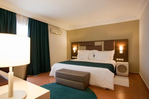 アガディールにあるケンジ ヨーロッパの大きなベッドと椅子が備わるホテルルームです。