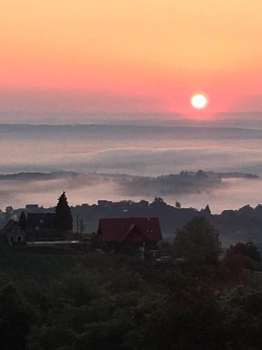 a sunset with the sun in the sky and clouds at Wohlmuth-Lückl in Kitzeck im Sausal