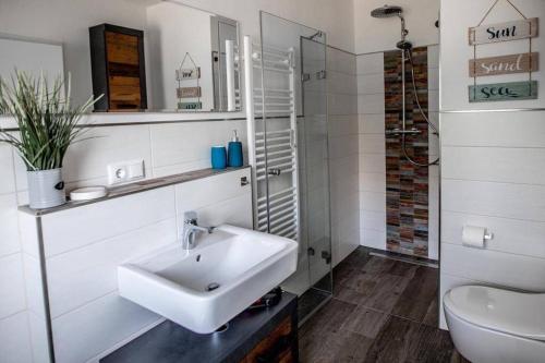 a white bathroom with a sink and a toilet at Ferienwohnung TinyBeach in Lubmin