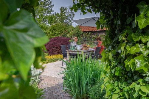two people sitting at a table in a garden at Boutique vakantiehuis Het Stalhuys in Reeuwijk