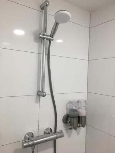 a shower head in a bathroom with white tiles at B&B Het Vogeltje in Harderwijk