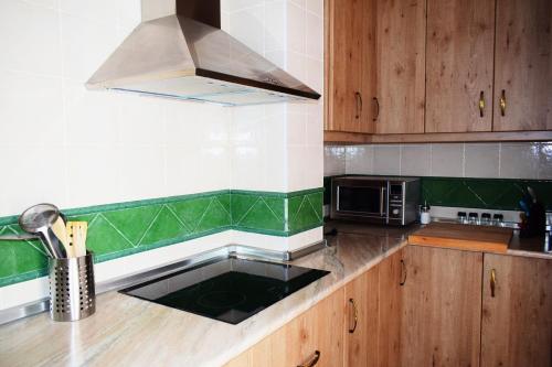 een keuken met houten kasten en groen en wit bij El Ático de La Casa Viva in Vélez Blanco
