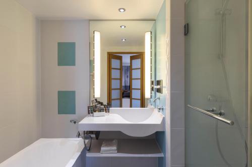 La salle de bains est pourvue d'un lavabo blanc et d'une douche. dans l'établissement Novotel Wolverhampton City Centre, à Wolverhampton