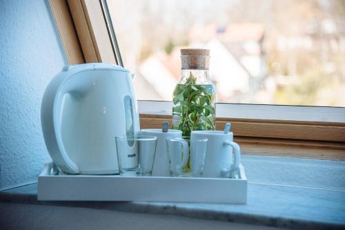 un estante con tazas y una botella en una ventana en Apartmenthaus Kaiser Friedrich, en Potsdam