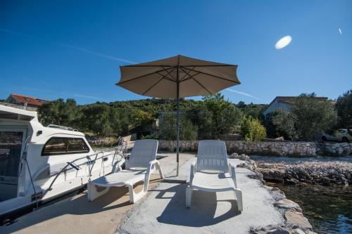 a group of chairs and an umbrella next to a boat at House Dino in Tkon