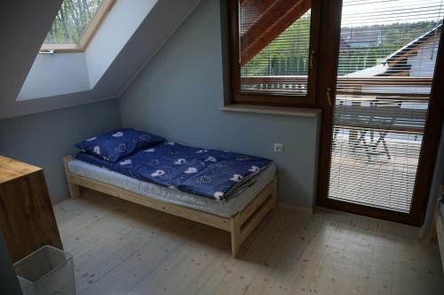 a small bed in a room with two windows at OSADA CZTERY PORY ROKU - DOM ZIMA in Kopalino