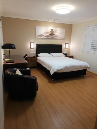 a bedroom with a large bed and a chair at BHA in Perth